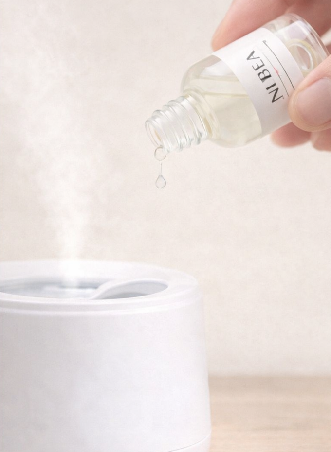 Esencia NUBEA en frasco junto a humidificador en ambiente cálido natural.